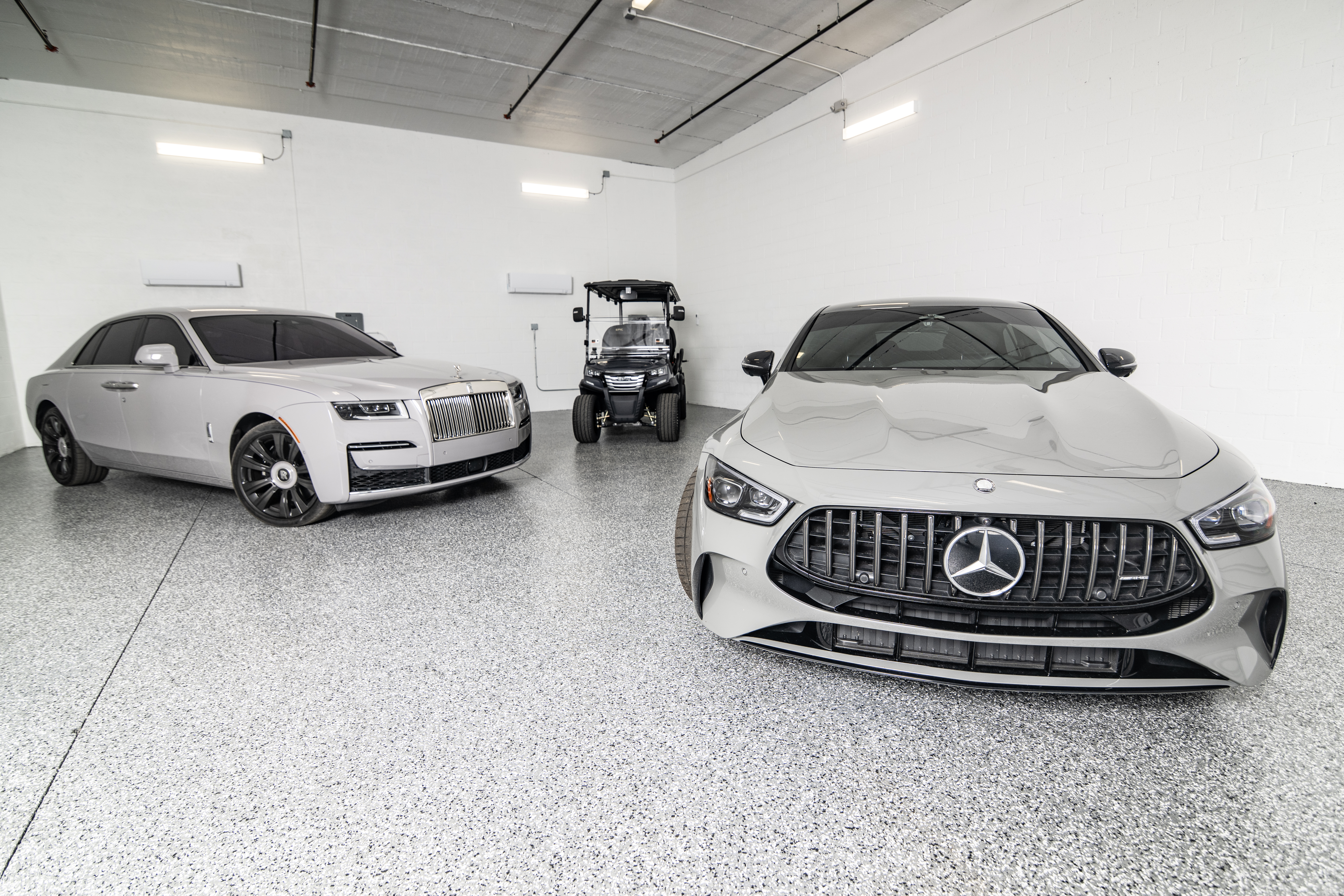 Rolls-Royce luxury sedan, Mercedes-AMG performance coupe, and golf cart parked inside a clean, climate-controlled private storage unit at MetroMaxx RV & Boat Storage.